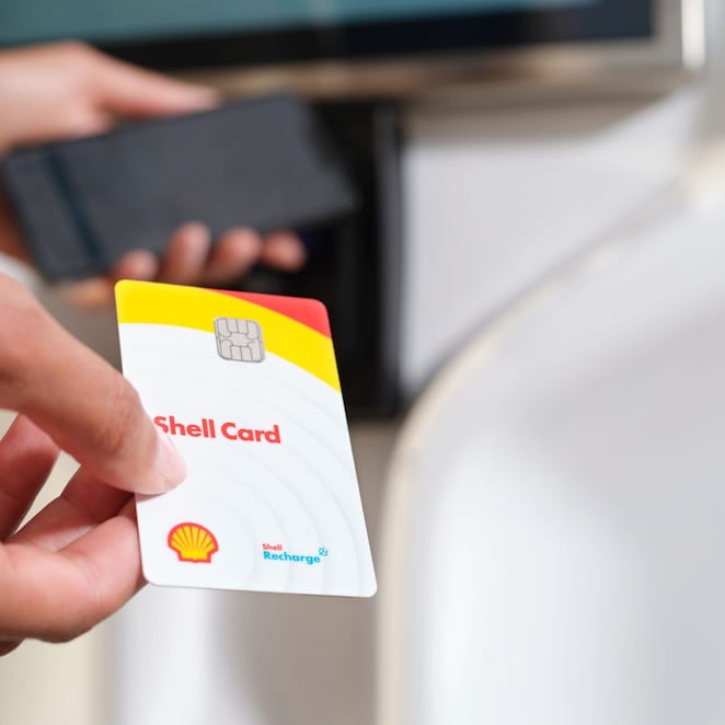 Eine Person hält eine Shell Card an einer Ladesäule