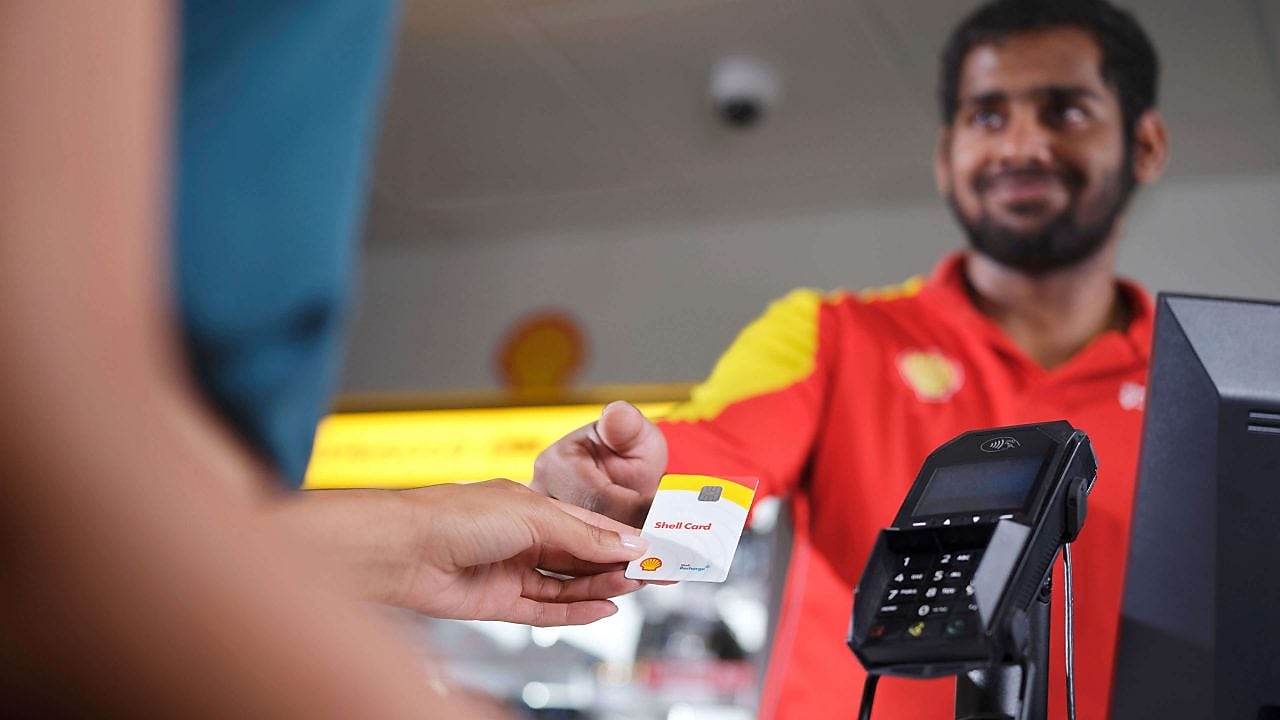 Eine Shell Card wird am Tresen dem Stationspersonal übergeben.