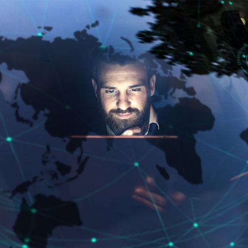 Ein Mann sitzt in seinem Auto und betrachtet sein Tablet. In der Windschutzscheibe spiegelt sich ein Head-up Display.