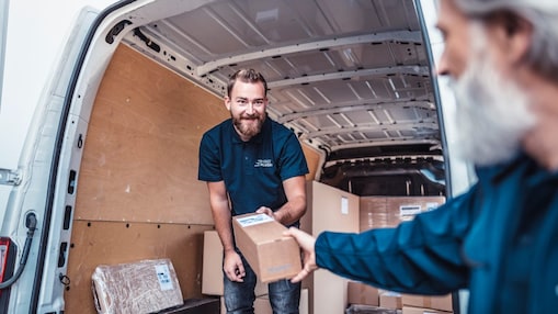 Ein Mann übergibt en Paket aus seinem Transporter.