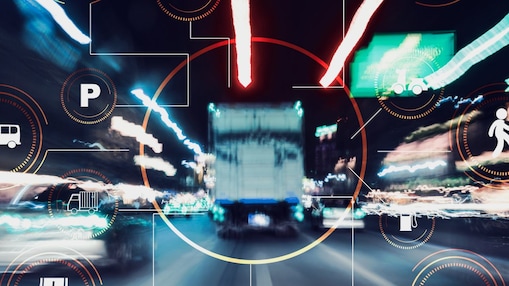 Das Bild zeigt eine Langzeitbelichtung einer belebten Straße bei Nacht, auf der die Lichtspuren vorbeifahrender Fahrzeuge zu sehen sind. Über das Foto sind verschiedene grafische Symbole und Icons gelegt, die sich auf Transport und Mobilität beziehen