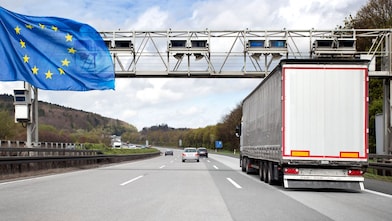Eine Mautbrücke auf einer befahrenen deutschen Autobahn. Es ist eine Europa-Flagge zu sehen.