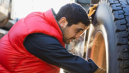Ein Lkw-Fahrer prüft den Reifen seines Lkw.