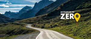 Auto fährt auf einer Schnellstraße durch grüne Landschaft mit Bergen im Hintergrund, Textaufschrift: "Accelerate to Zero"Auto fährt auf einer Schnellstraße durch grüne Landschaft mit Bergen im Hintergrund, Textaufschrift: "Accelerate to Zero".