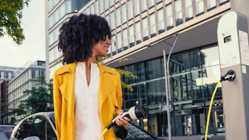 Frau schaut auf Kostenanzeige beim aufladen ihres Elektroautos
