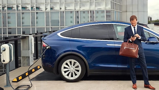 Employee standing in front of electric company car