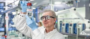 Labormitarbeiter der ein Fläschen GTL Fuel hochhält