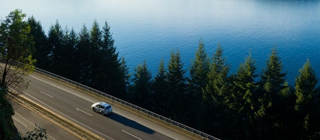 Ein Auto fährt auf einer Straße an einem See.