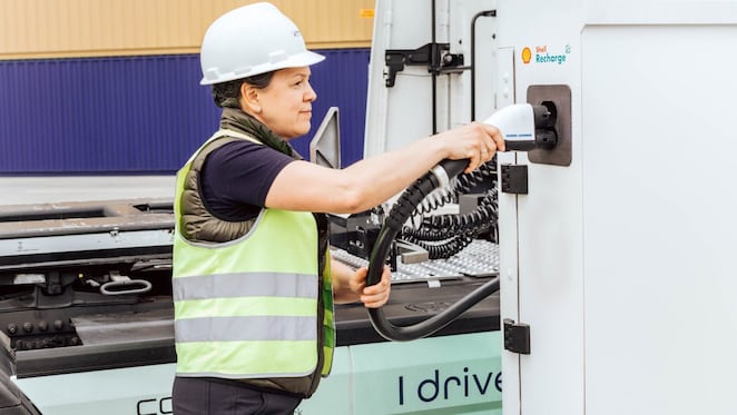 Lkw-Fahrerin steckt gerade den Ladestecher an einem Shell Recharge Ladedepot an.