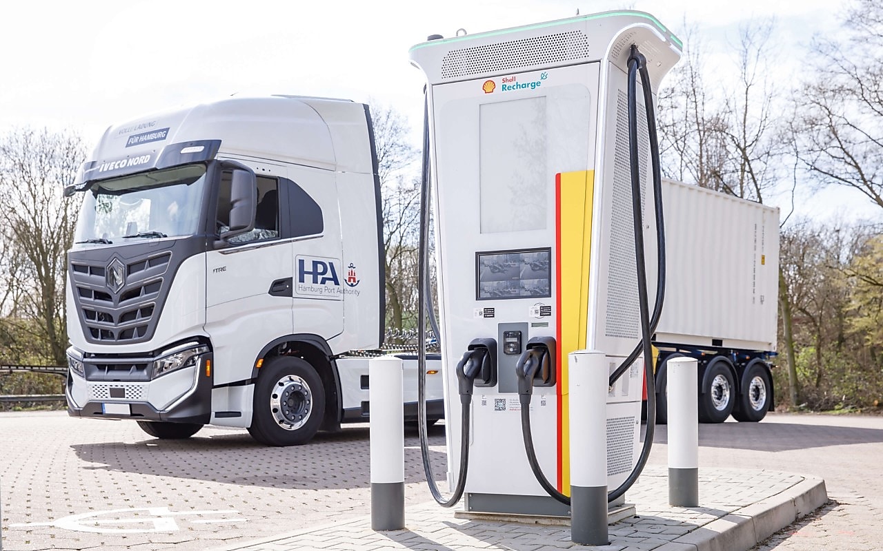 Das Bild zeigt einen E-Lkw, der an einer Shell Hochleistungs-Ladestation an einer Straße geladen wird.