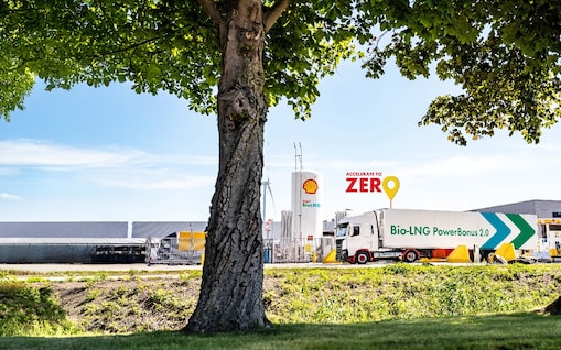 Ein LNG Lkw steht an eine LNG Station hinter einem Baum