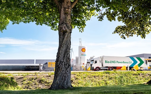 Ein LNG Lkw steht an eine LNG Station hinter einem Baum