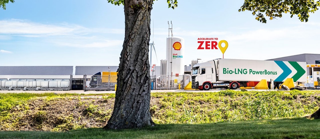 Ein LNG Lkw steht an eine LNG Station hinter einem Baum