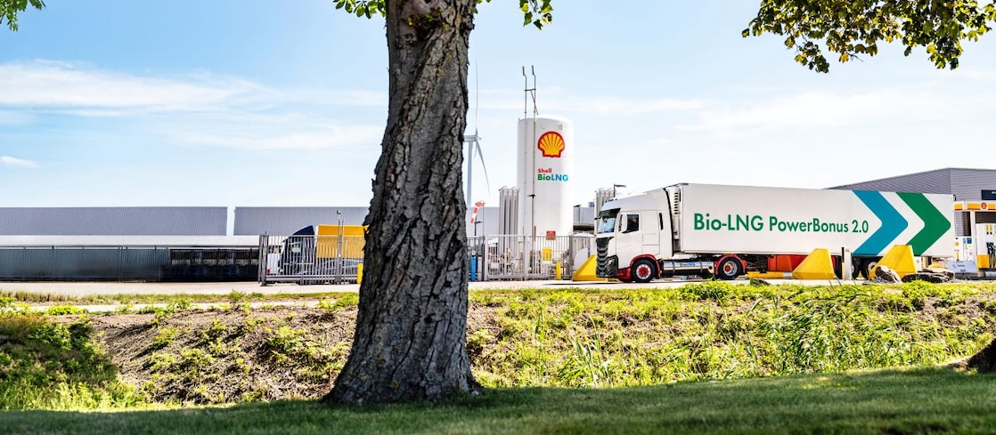 Ein LNG Lkw steht an eine LNG Station hinter einem Baum