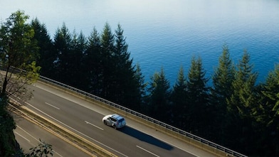 Ein Auto fährt auf einer Straße an einem See.