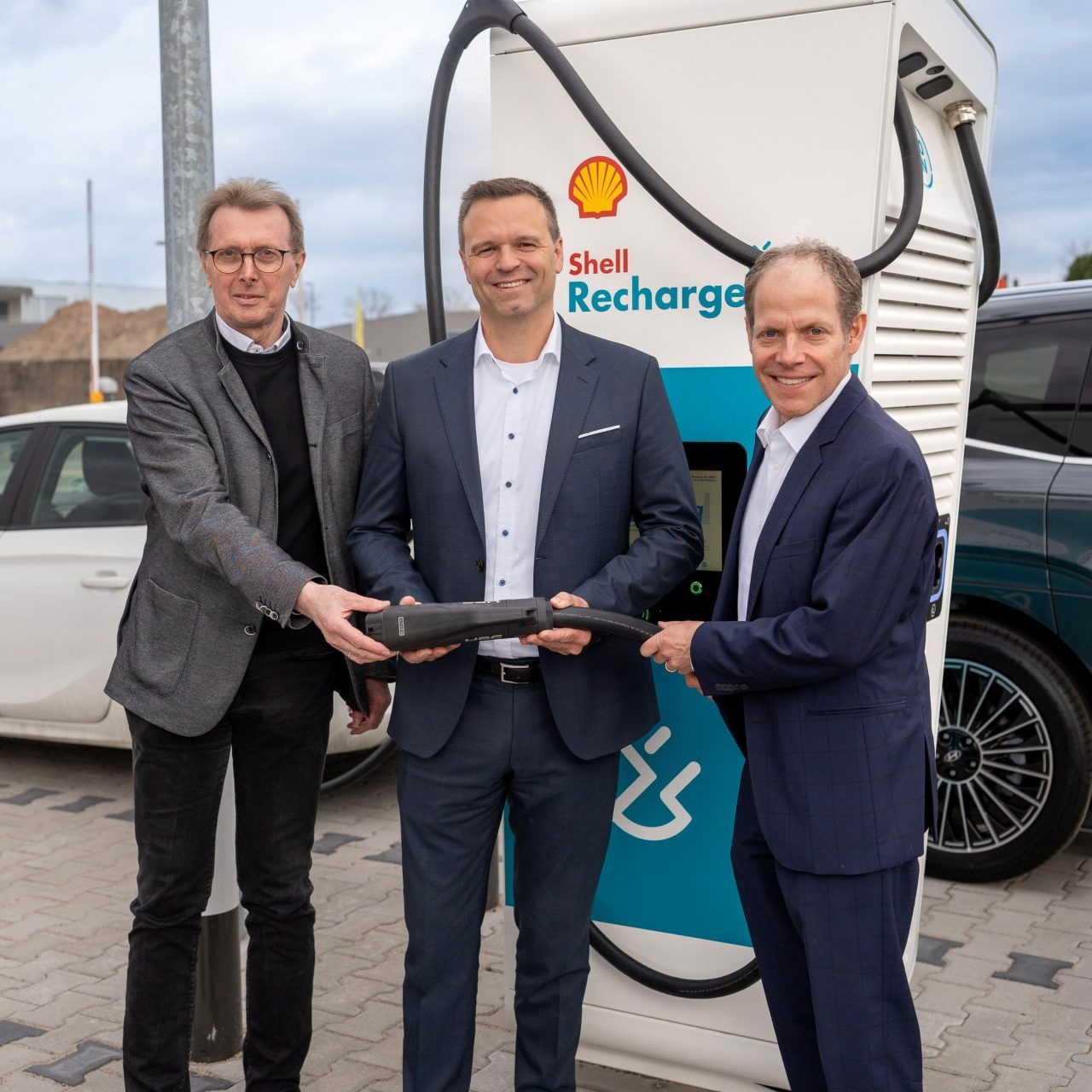 Mitarbeiter von SAP in Walldorf halten einen Shell Recharge Ladestecker