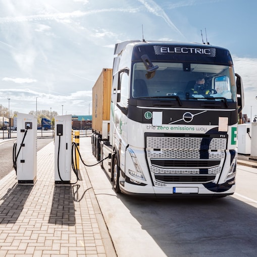 Ein E-Lkw - beladen mit einem Container - steht an einer Ladesäule.