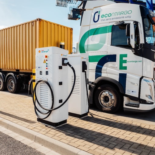 Ein E-Lkw - beladen mit einem Container - steht an einer Ladesäule.