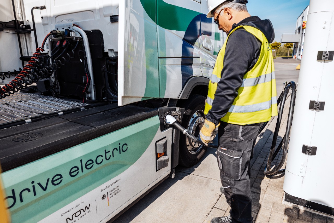 Ein Mann steckt seinen E-Lkw an.