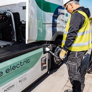 Ein Mann steckt seinen E-Lkw an.