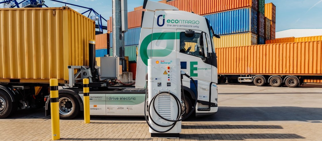 Ein E-Lkw - beladen mit einem Container - steht an einer Ladesäule.