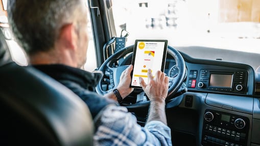 Ein Fahrer im Cockpit eines Lkw bedient sein Tablet.