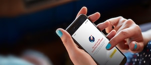 Frau sitzt im Auto und hält in der Hand ein Handy mit geöffneter Shell App und fertig eingerichtetem Shell SmartPay