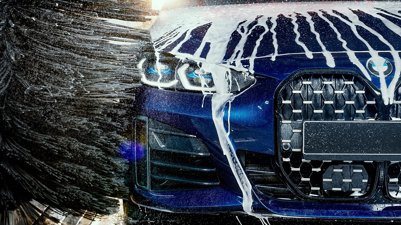 Eine junge Frau berührt ein blaues Auto