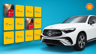 Weisser Mercedes-SUV rechts im Bild, links daneben ein gelbes Shell-Car-Wash-Memory-Spiel mit aufgedeckten Autowasch-Karten vor blauem Hintergrund, Shell-Logo oben rechts in der Ecke.