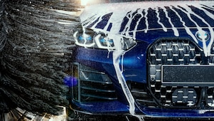 Frauenhand fährt über glänzende Autolack nach der Autowäsche an Shell Station