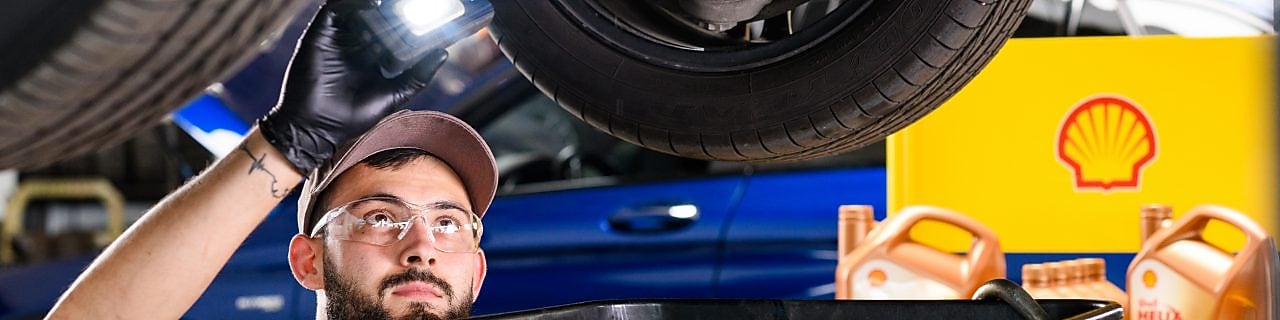 Motorölwechsel in der Werkstatt: Fachkraft füllt Shell Helix Ultra Motoröl in den Motor eines Pkw – optimale Schmierung, Motorschutz und Leistungsfähigkeit durch hochwertige Shell Schmierstoffe.