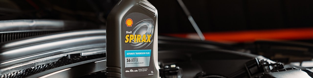 Shell Spirax S6 ATF X Getriebeölflasche im Motorraum eines Fahrzeugs, aufgenommen in einer Werkstattumgebung.