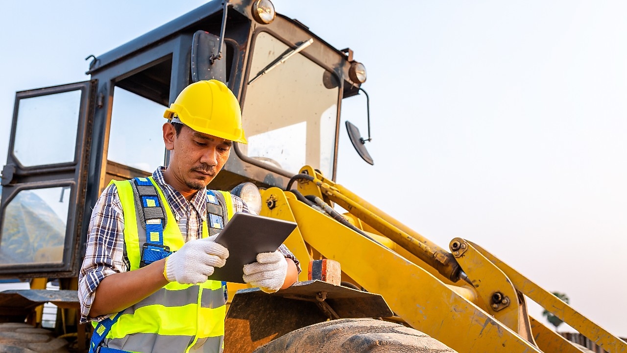Shell worker leaning on buldozer.