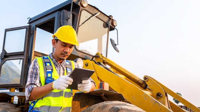 Shell worker leaning on buldozer.