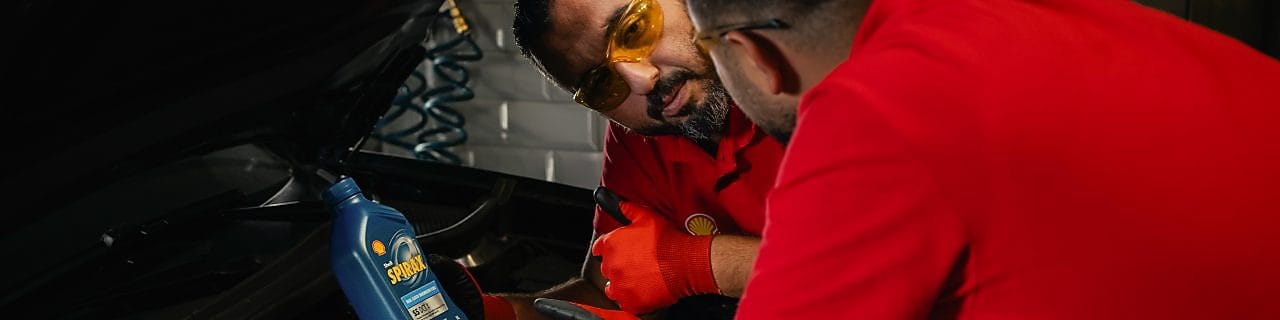 Mechaniker bei der Wartung eines Fahrzeugs im Motorraum, Anwendung von hochwertigen Schmierstoffen zur optimalen Motorleistung