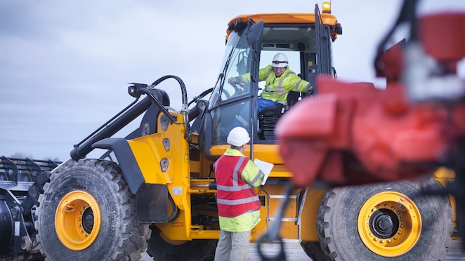 Shell worker working on field with heavy machines