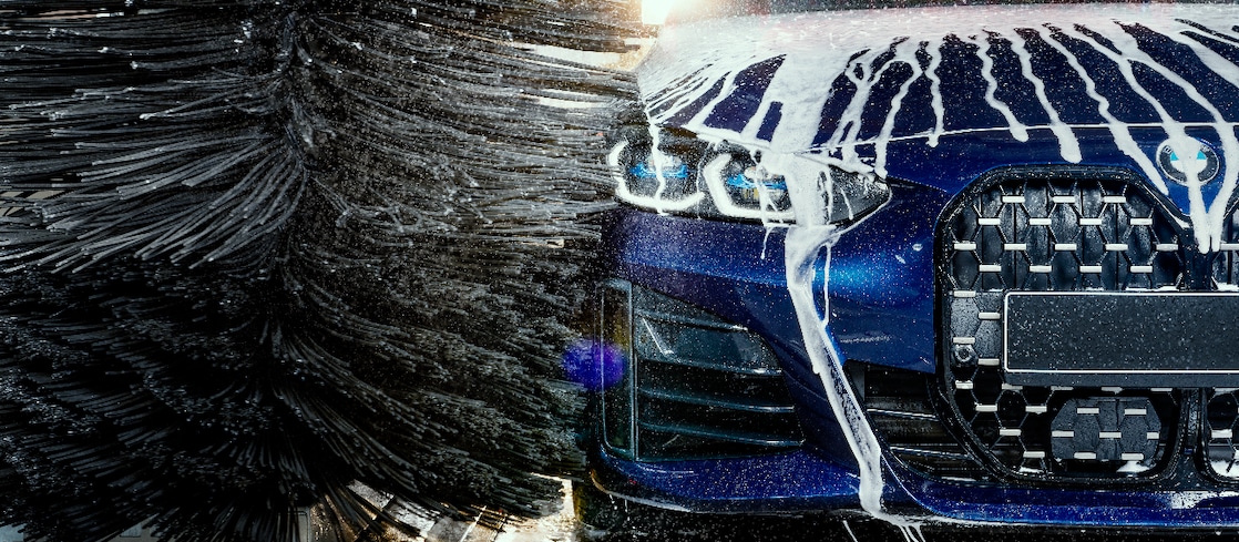 Eine junge Frau berührt ein blaues Auto