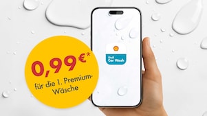 Eine Hand hält ein Smartphone mit der Shell Car Wash App auf dem Display. Links daneben ist ein großer gelber Kreis mit einem Werbeangebot in roter und dunkelgrauer Schrift zu sehen: „0,99 €* für die 1. Premium-Wäsche". Der Hintergrund ist hellgrau mit Wassertropfen-Elementen.