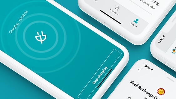 A female hand is holding a plug and charging an electric car, with a bright sun light and blue sky in the background