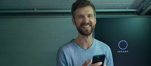Lächelnder Mann mir einem Smartphone vor einer sonnen Batterie