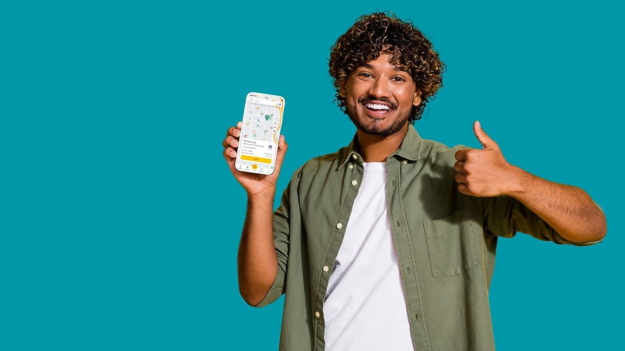 Lächelnder junger Mann mit der neuen Shell App auf dem Smartphone