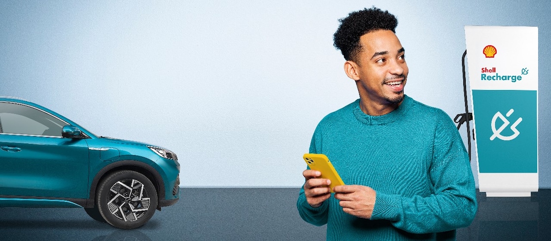 Ein Mann mit gelbem Smartphone steht neben einem blauen BYD E-Auto und einer Shell Recharge Ladestation.