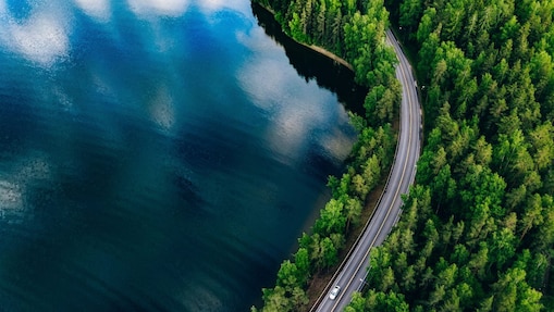 E-Auto auf einer Straße im Wald an einem See