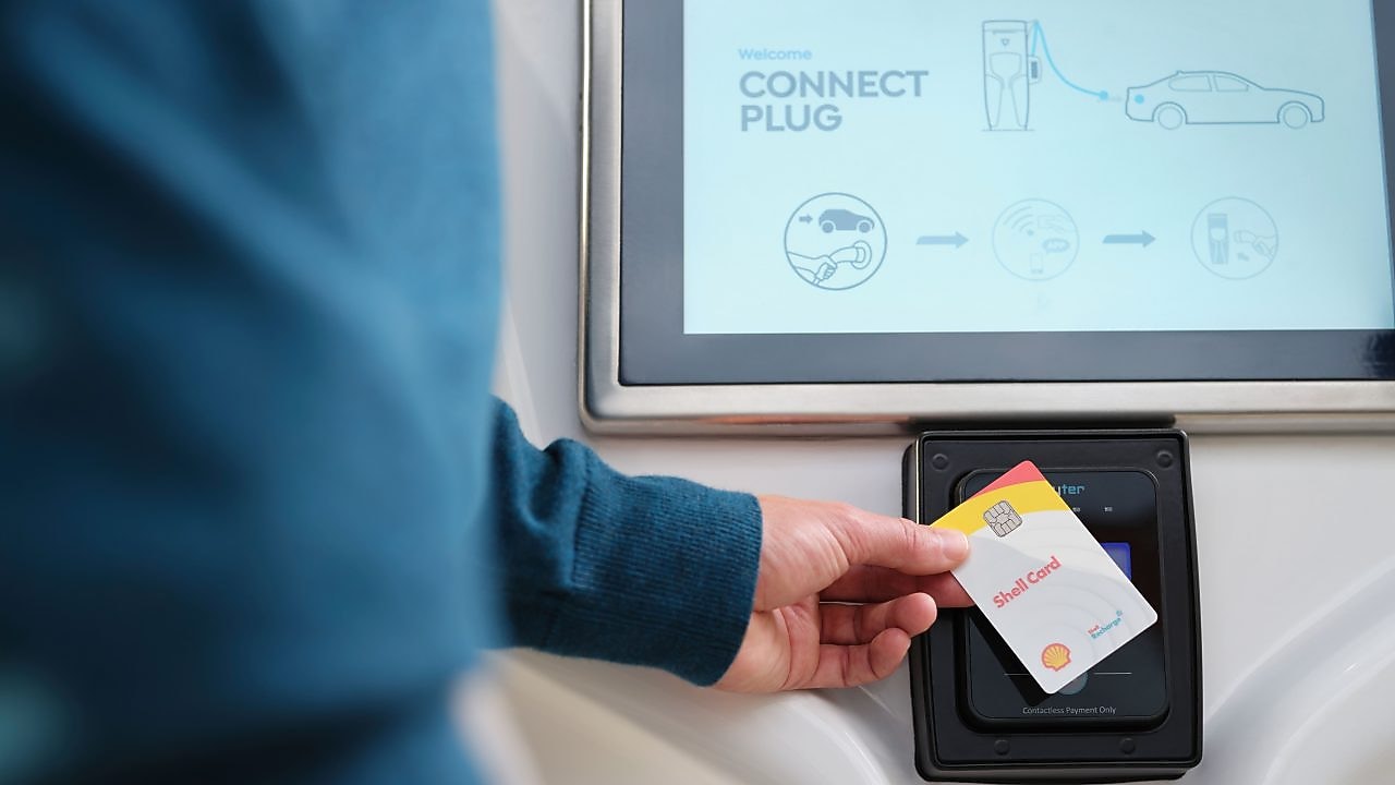 Person hält Shell Card an einer Shell Recharge Ladestation.