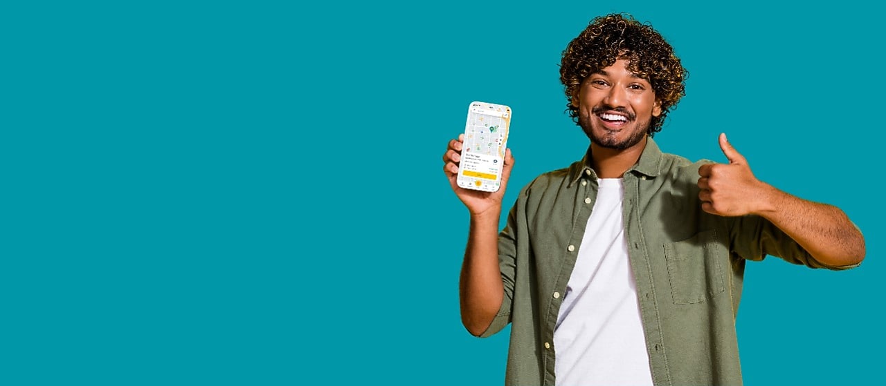 Lächelnder junger Mann mit der neuen Shell App auf dem Smartphon