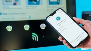 Smartphone vor einer E-Ladestation während eines aktiven Ladevorgangs mit der Shell App.