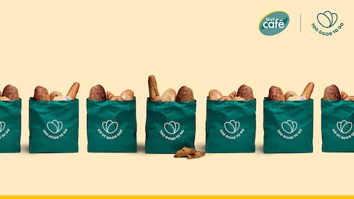 Too Good To Go Überraschungstüten auf sandfarbenem Hintergrund. Text: Wir feiern 500.000 gerettete Magic-Bags